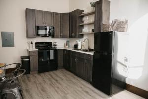 a kitchen with wooden cabinets and a black refrigerator at The Neighborhood Lofts in Greencastle