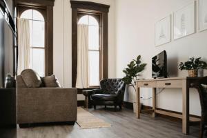 a living room with a chair and a desk and two windows at The Neighborhood Lofts in Greencastle