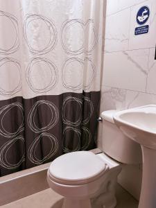 a bathroom with a toilet and a shower curtain at HOTEL ALFONSO UGARTE in Chiclayo