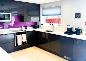 a kitchen with black and white cabinets and a sink at The Lockside By Allsquare Stays 5BDR Heathrow M4 M25 M3 in Staines
