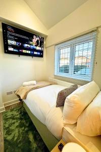 a bedroom with a large bed and a flat screen tv at The Lockside By Allsquare Stays 5BDR Heathrow M4 M25 M3 in Staines