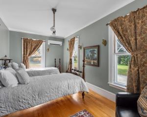 a bedroom with two beds and two windows at The Mulburn Inn in Bethlehem