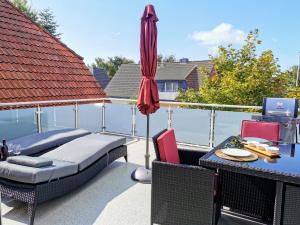 a patio with a table and an umbrella and a table and chairs at Moderne Wohnung mit Privatpool in Büsum