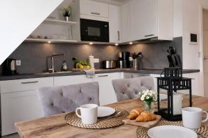 a kitchen with a table with cups and croissants on it at Moderne Wohnung mit Privatpool in Büsum