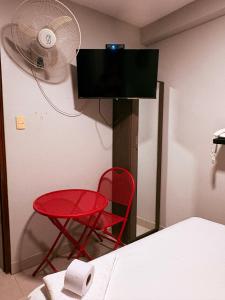a room with a red chair and a fan at HOTEL ALFONSO UGARTE in Chiclayo