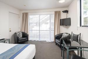 a hotel room with a bed and a desk and chairs at ASURE Phoenix Motor Inn in Blenheim