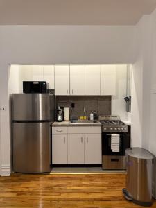 a kitchen with white cabinets and a stainless steel refrigerator at The Broadway Escape - Private Room in Times Square in New York