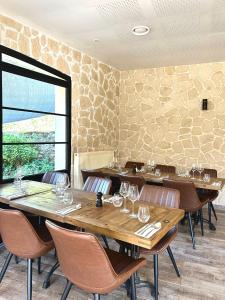 a restaurant with wooden tables and chairs and a stone wall at Gîtes de la Renaissance in Merlieux-et-Fouquerolles