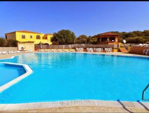a large blue swimming pool with chairs and tables at Sardegna selvaggia a due passi dal mare in Vignola Mare