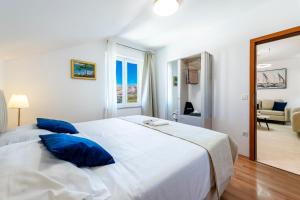 a bedroom with a large white bed with blue pillows at Villa Nick in Cavtat