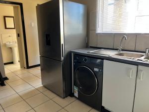 a kitchen with a refrigerator and a washing machine at The Grey Ivory in Port Alfred +2 photos