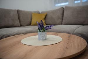 a vase with purple flowers sitting on a coffee table at Phenix Apartments Lux Parking FREE in Podgorica