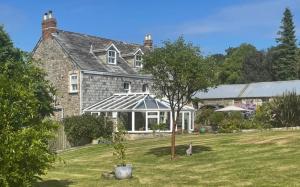 a large stone house with a cat sitting in the yard at Treveighan Farmhouse in Saint Teath