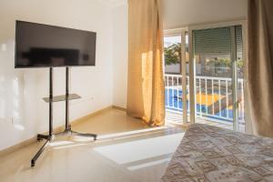 a bedroom with a flat screen tv and a balcony at El Laurel, Remote Work Friendly, City Center in Los Llanos de Aridane