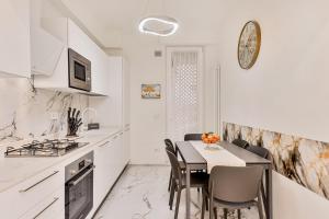 a white kitchen with a table and chairs and a stove at luxury apartament in Viareggio +10 photos