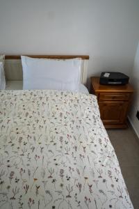 a bed with a white bedspread with flowers on it at Villa Gaia Novi Grad in Jablanica