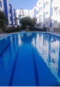 a large blue swimming pool with buildings in the background at Suite Home martil in Martil