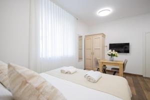 a white bedroom with two beds and a table at Split Varos Inn in Split