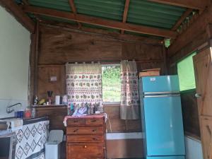 a kitchen with a refrigerator and a window at Camping caminho das pedras in São Bento do Sapucaí