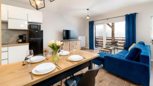 a kitchen and living room with a table and a blue couch at Apartamenty Ewa in Karpacz