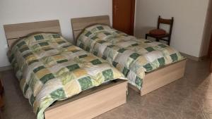 two twin beds in a bedroom with a chair at La Panchina sul Corso in Grassano