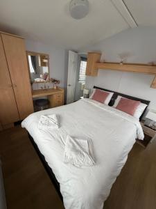 a bedroom with a large bed with white sheets and red pillows at Vacation Escape - Valley Farm -Clacton-on-sea - Holiday Park in Clacton-on-Sea