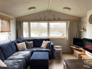 a living room with a blue couch and a tv at Rockley Park - Coral in Poole