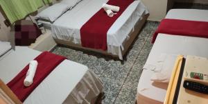 ein Zimmer mit zwei Betten mit rot-weißer Bettwäsche in der Unterkunft Ferrari's Hotel in Birigui