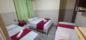 ein Zimmer mit zwei Betten mit rot-weißer Bettwäsche in der Unterkunft Ferrari's Hotel in Birigui