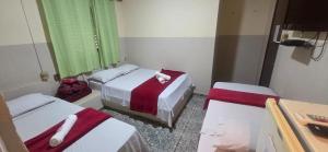 ein Zimmer mit zwei Betten mit rot-weißer Bettwäsche in der Unterkunft Ferrari's Hotel in Birigui