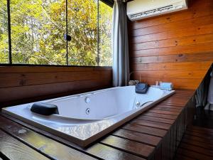 a large bath tub in a room with windows at Romantic nature retreat | Hot tub and fireplace in São Pedro de Alcântara +61 photos
