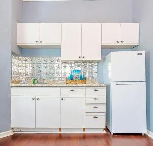a kitchen with white cabinets and a white refrigerator at Surf & Strand Unit B in Galveston