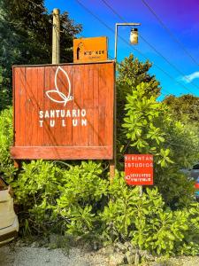 a sign for a santiago institution sitting in some bushes at Family Studio Suite with Kitchenette & Terrace - Santuario Hotel Boutique in Chemuyil
