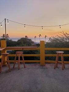 a bench with two stools and a view of the ocean at Yellow Submarine Hostal in Poneloya