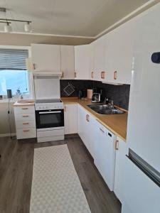 a kitchen with white cabinets and a sink at Lyngen apartment in Lyngseidet