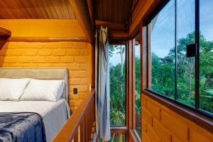 a bedroom with a bed and a large window at Chalé com hidro em meio a natureza in Brasília
