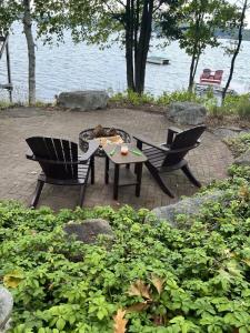 two chairs and a table in front of the water at Big Arbor Pines Family friendly in Woodruff