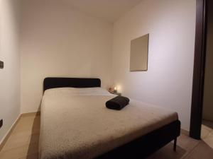 a bed in a white room with a black head board at Charme rustico con ampio giardino e piscina con due camere in Carrara