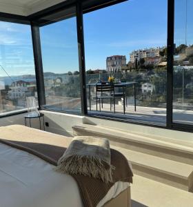 a bedroom with a bed and a table in front of windows at Villa Luna maison d'architecte in Marseille