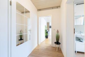 a bathroom with white walls and a hallway with potted plants at Orange Suite Schliengen 1 in Schliengen +17 photos