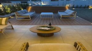 a patio with chairs and a table and a bottle of beer at The Haven - Ettalong in Ettalong Beach