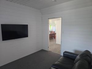 a living room with a couch and a flat screen tv at Horseshoe House - Gympie in Gympie