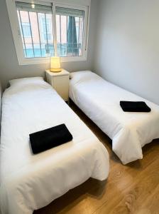 two beds in a room with a window at Sevilla Family House - La casa de Marta in Montequinto