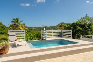 a swimming pool on a patio with a chair at LODGE LE Filaos in Sainte-Anne
