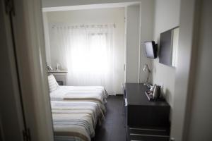 Habitación de hotel con 3 camas y ventana en Hostal Cabo Mayor, en Santander