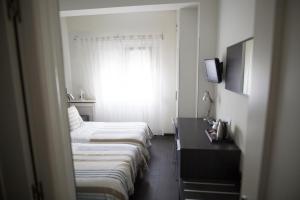 une chambre d'hôtel avec trois lits et une fenêtre dans l'établissement Hostal Cabo Mayor, à Santander
