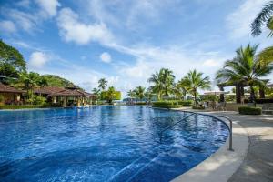 a swimming pool at a resort with palm trees at Veranda 4B 3 bdr Golf Course View in Los Suenos in Herradura