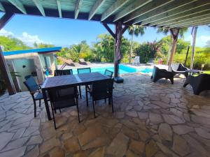 a patio with a table and chairs and a pool at Swisstropiclodges avec piscine privée in Sainte-Anne
