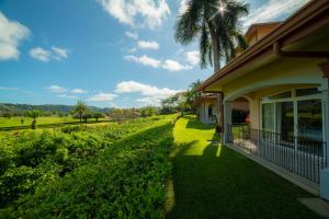 a house with a palm tree next to a yard at Colina 5E 2 bdr Garden View in Los Suenos in Jacó
