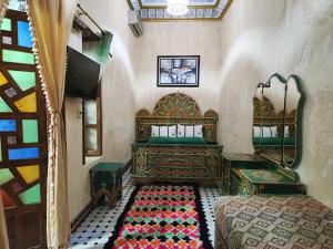 a bedroom with a bed and a tv and a mirror at Riad Fés blida in Fez